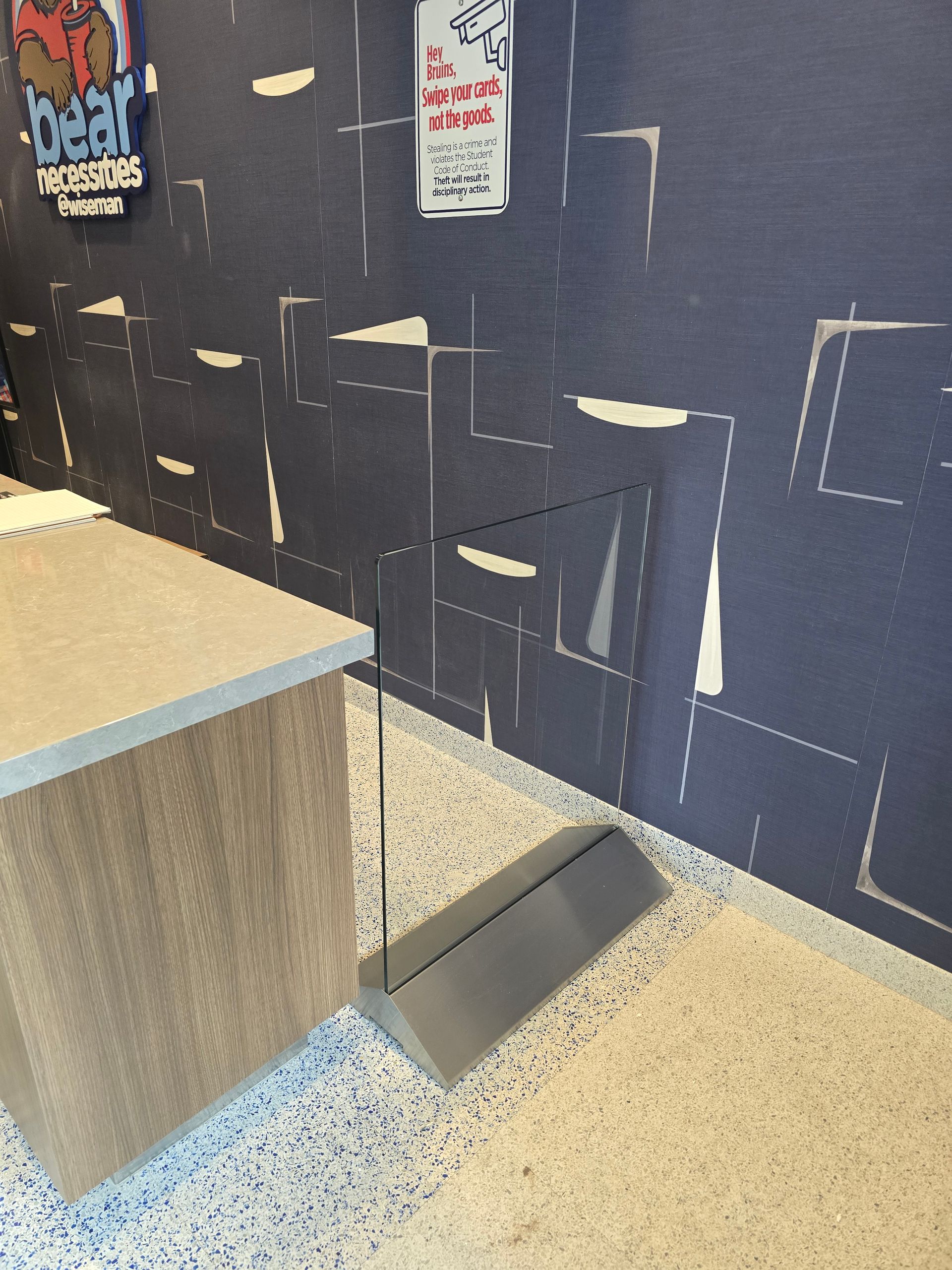 A counter with a metal base on a speckled floor, and a damaged blue wall.
