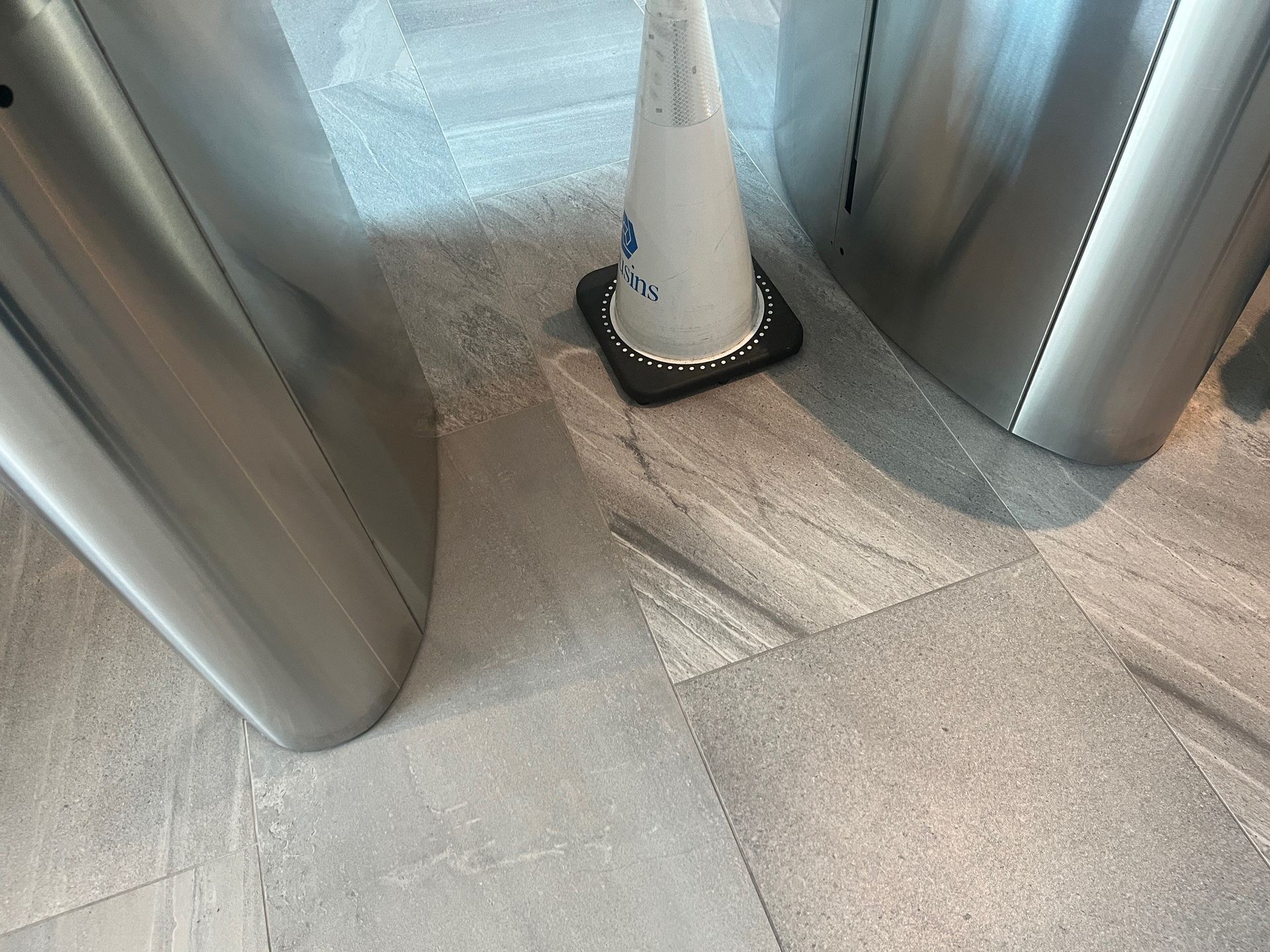 Floor with security turnstiles and a white traffic cone.