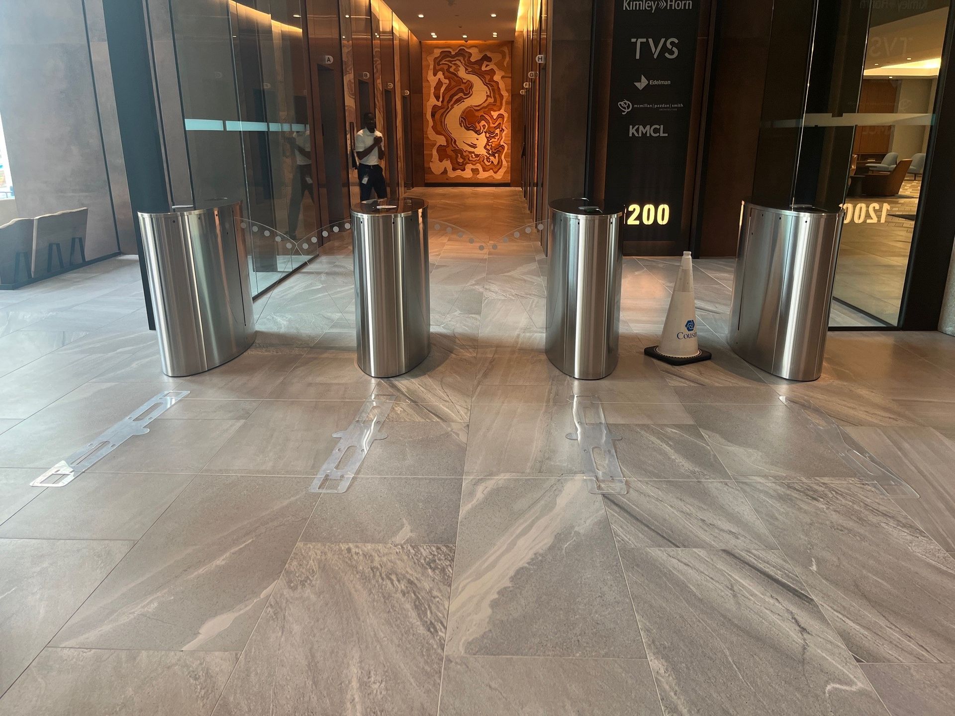 Turnstiles in a building entryway with polished stone flooring and a decorative dragon on a wall.