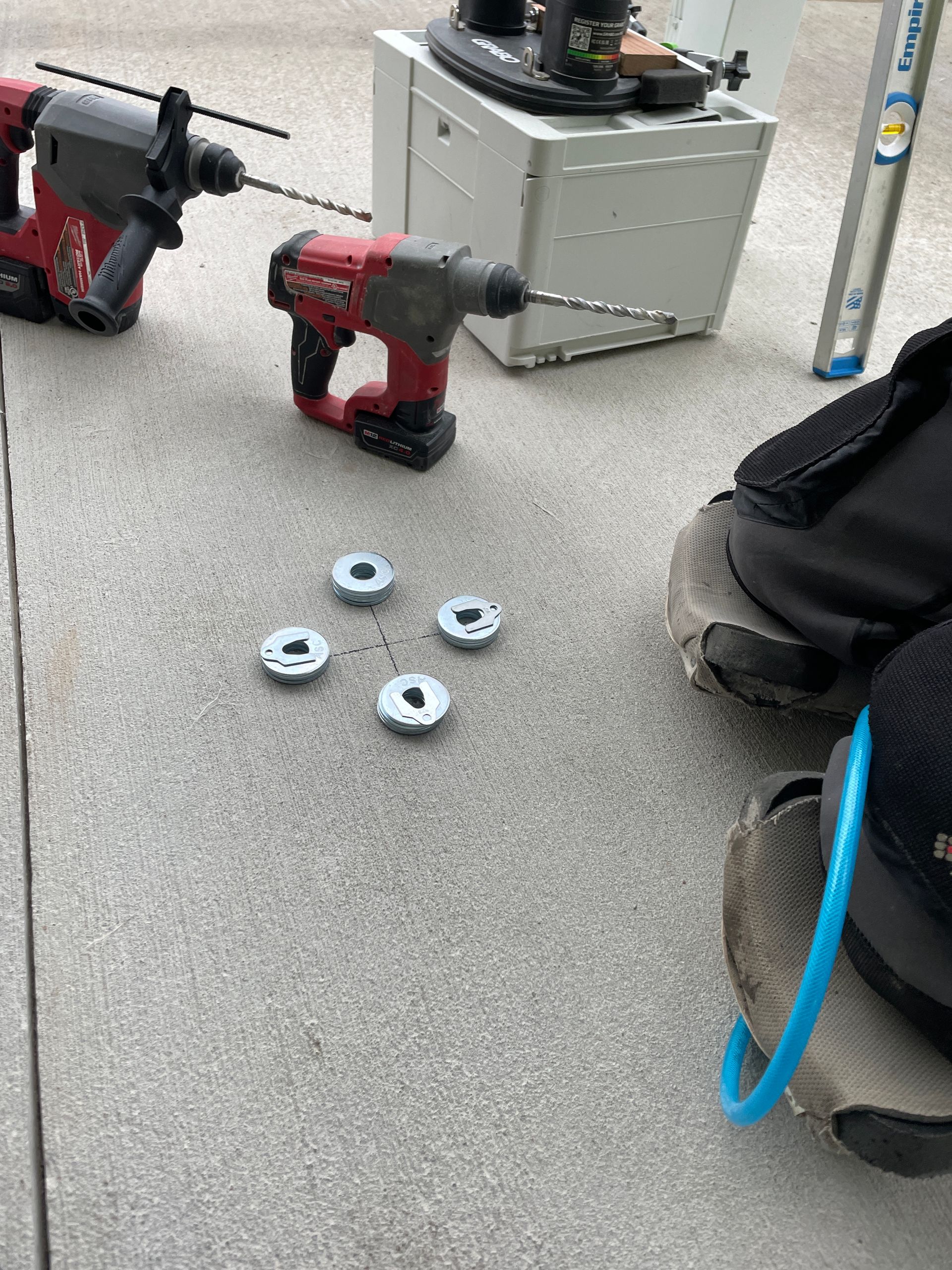 Four washers on concrete, surrounded by power tools and a work boot.