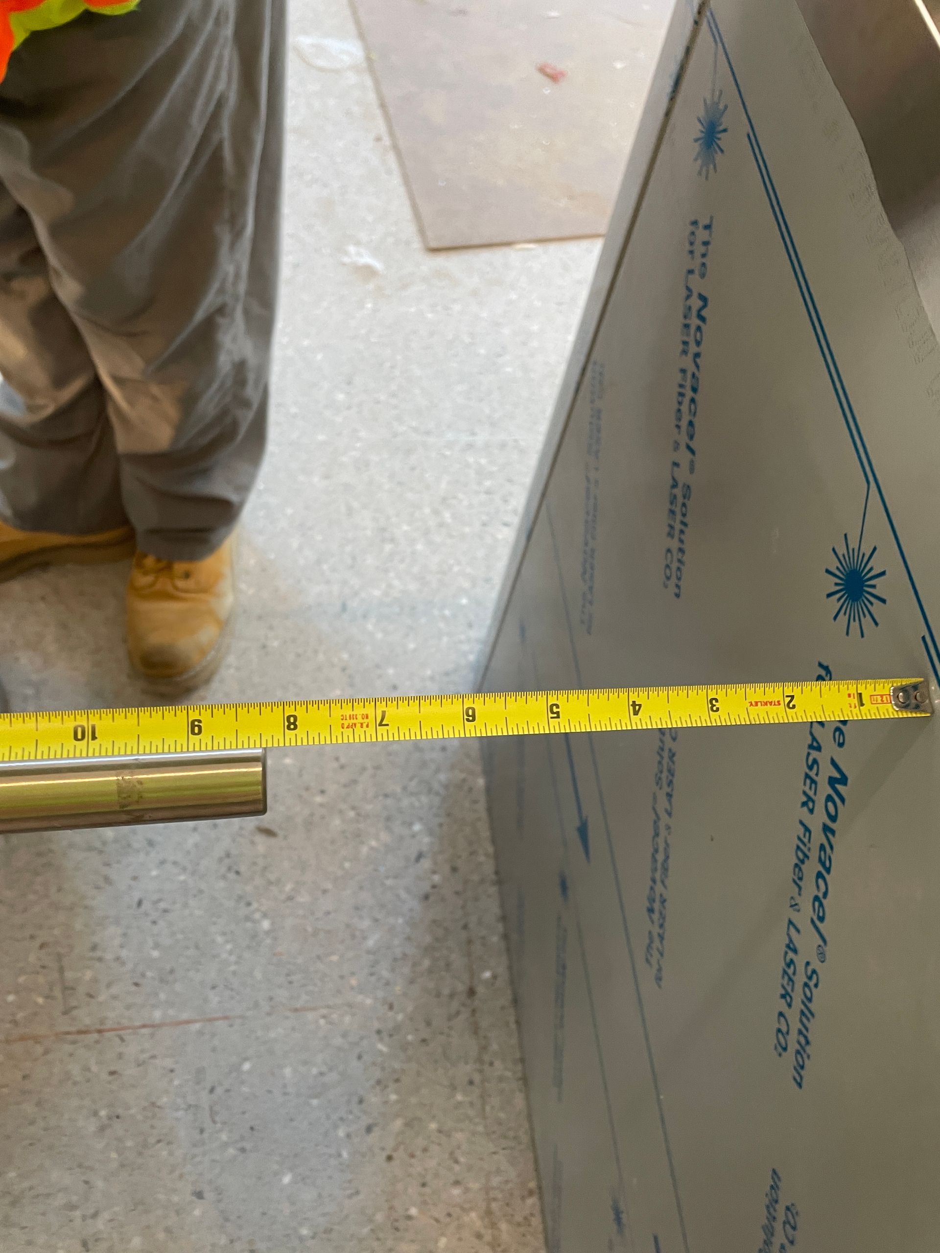 Person using a tape measure to measure a stainless steel corner of a structure.