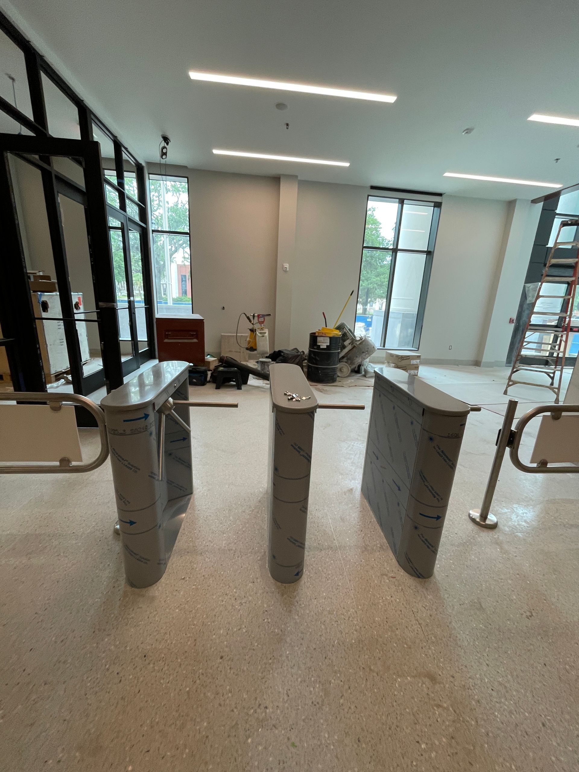 Three gray turnstiles in a building entrance, partially obscuring the view behind them.