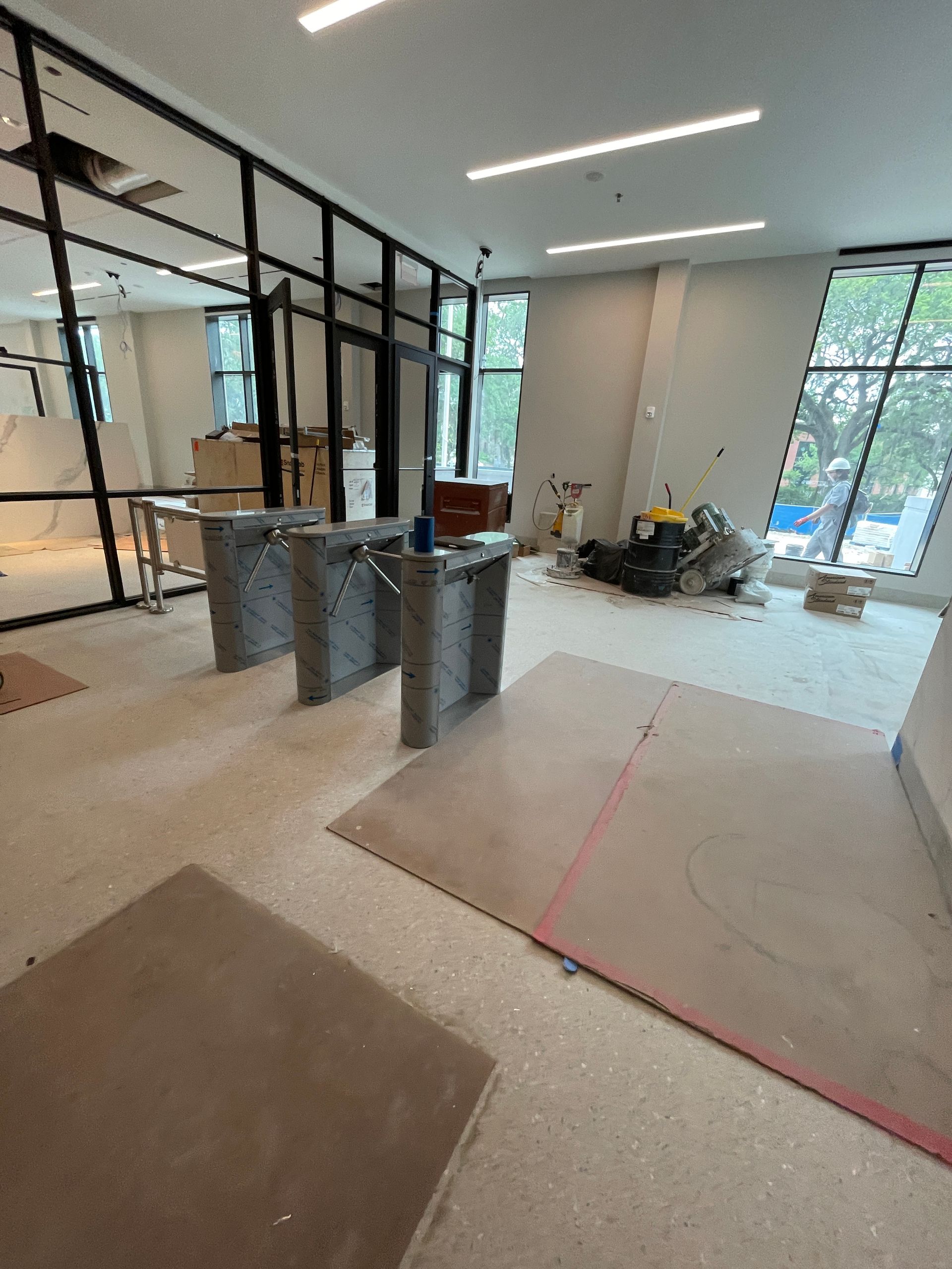 Interior construction site with gray blocks, glass walls, and debris.