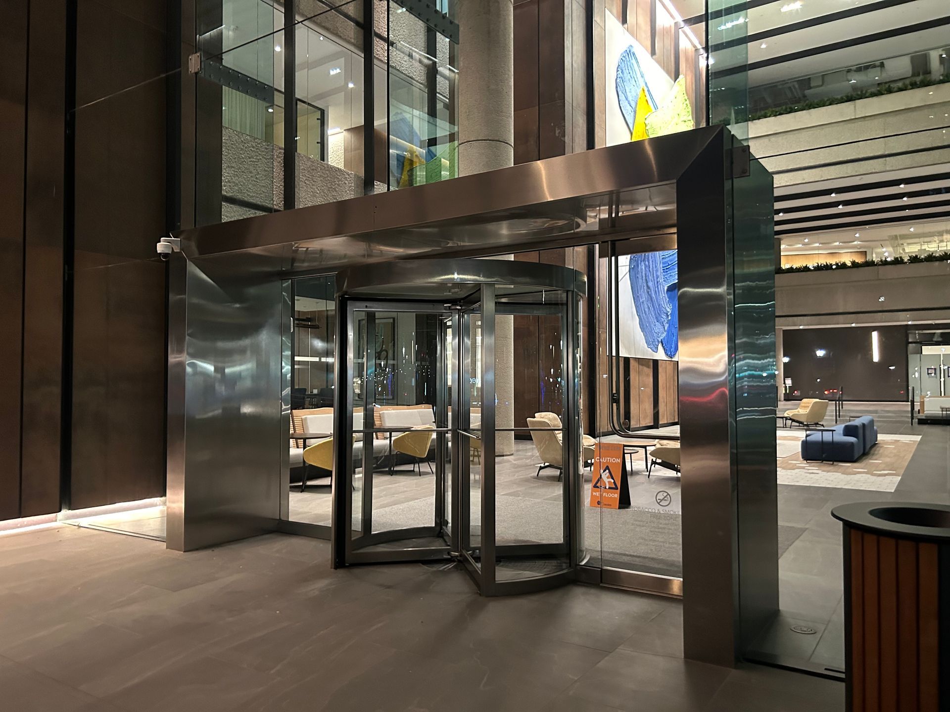 Revolving door entrance to a building with glass doors and stainless steel frame.