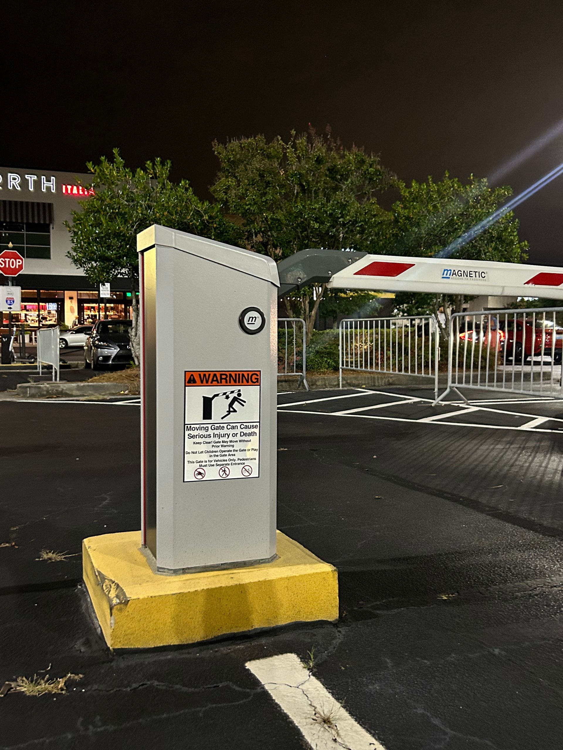 Parking lot entry kiosk with barrier gate, warning signs. 