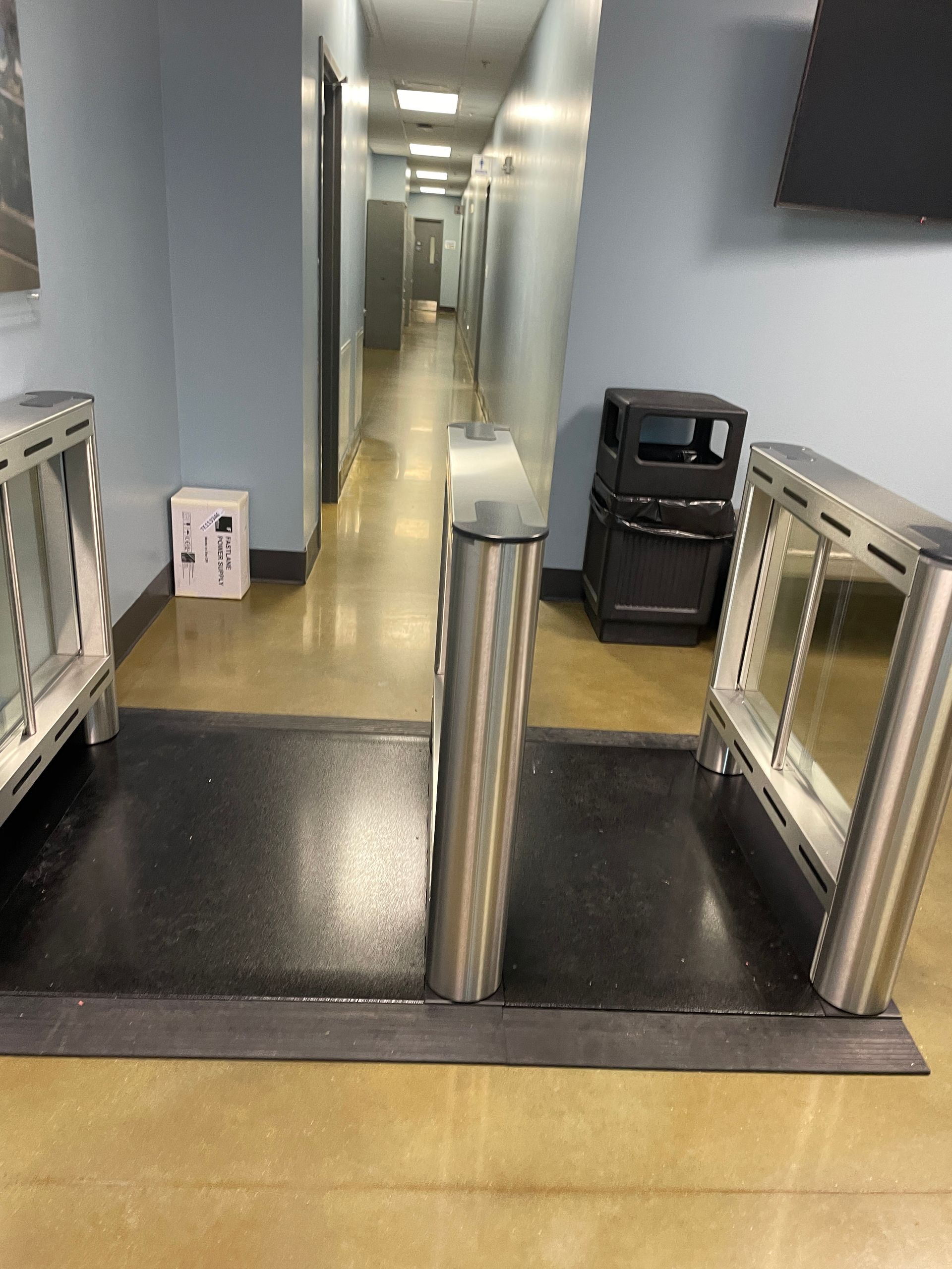 Hallway with security turnstiles and trash can.