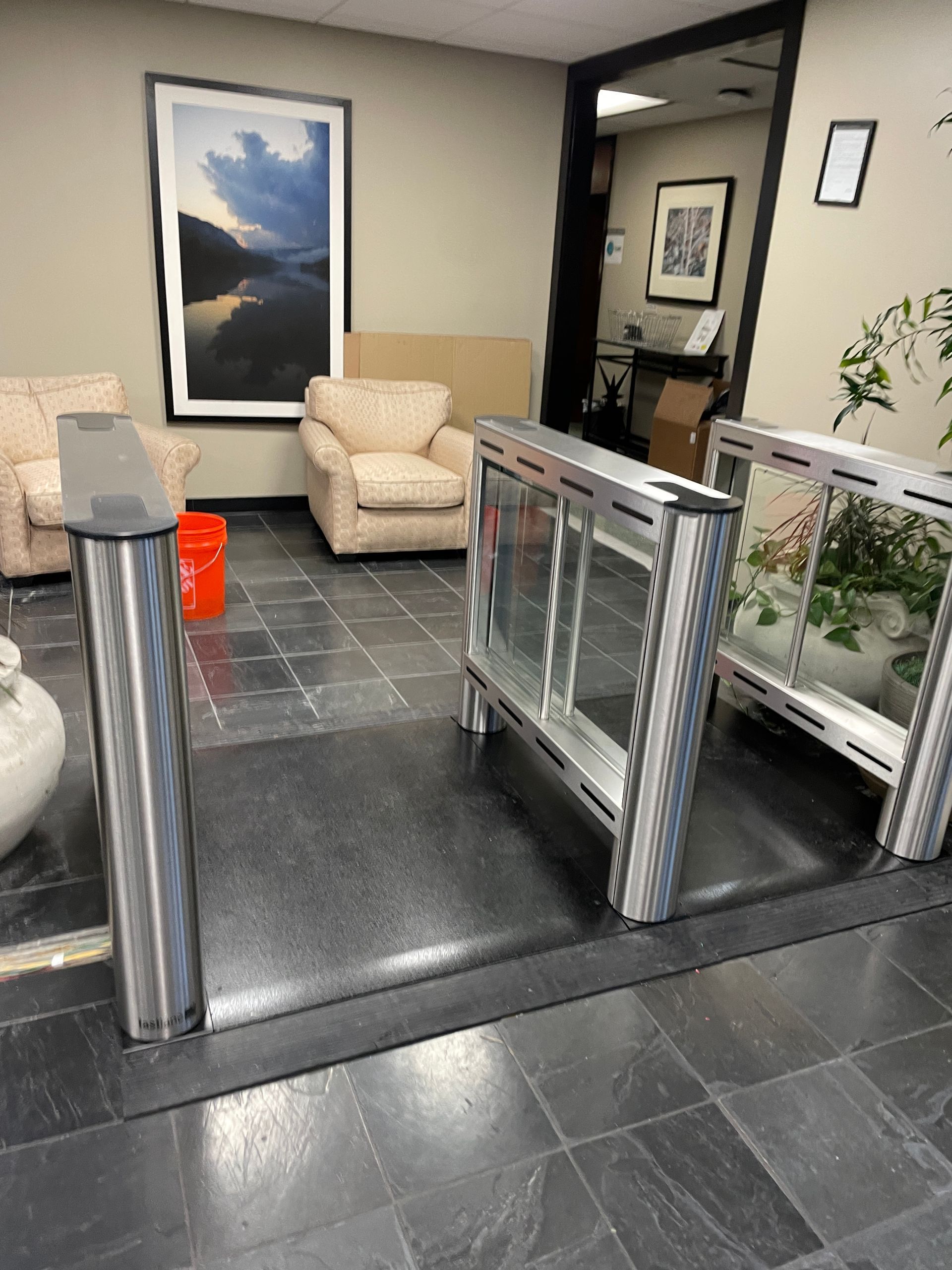 Office lobby with security turnstiles and waiting area with seating and art.
