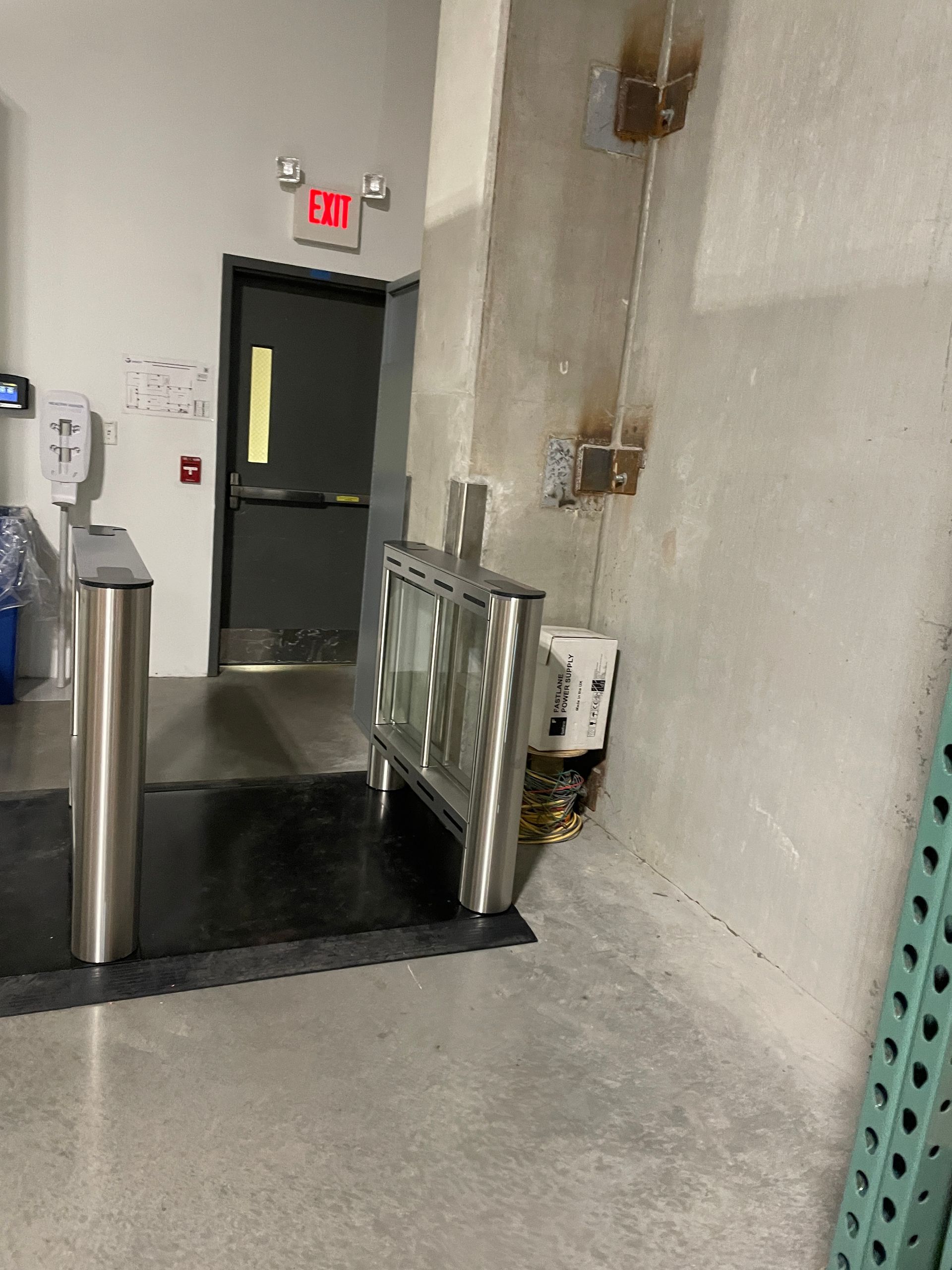 Metal security turnstile near a doorway with an Exit sign. 
