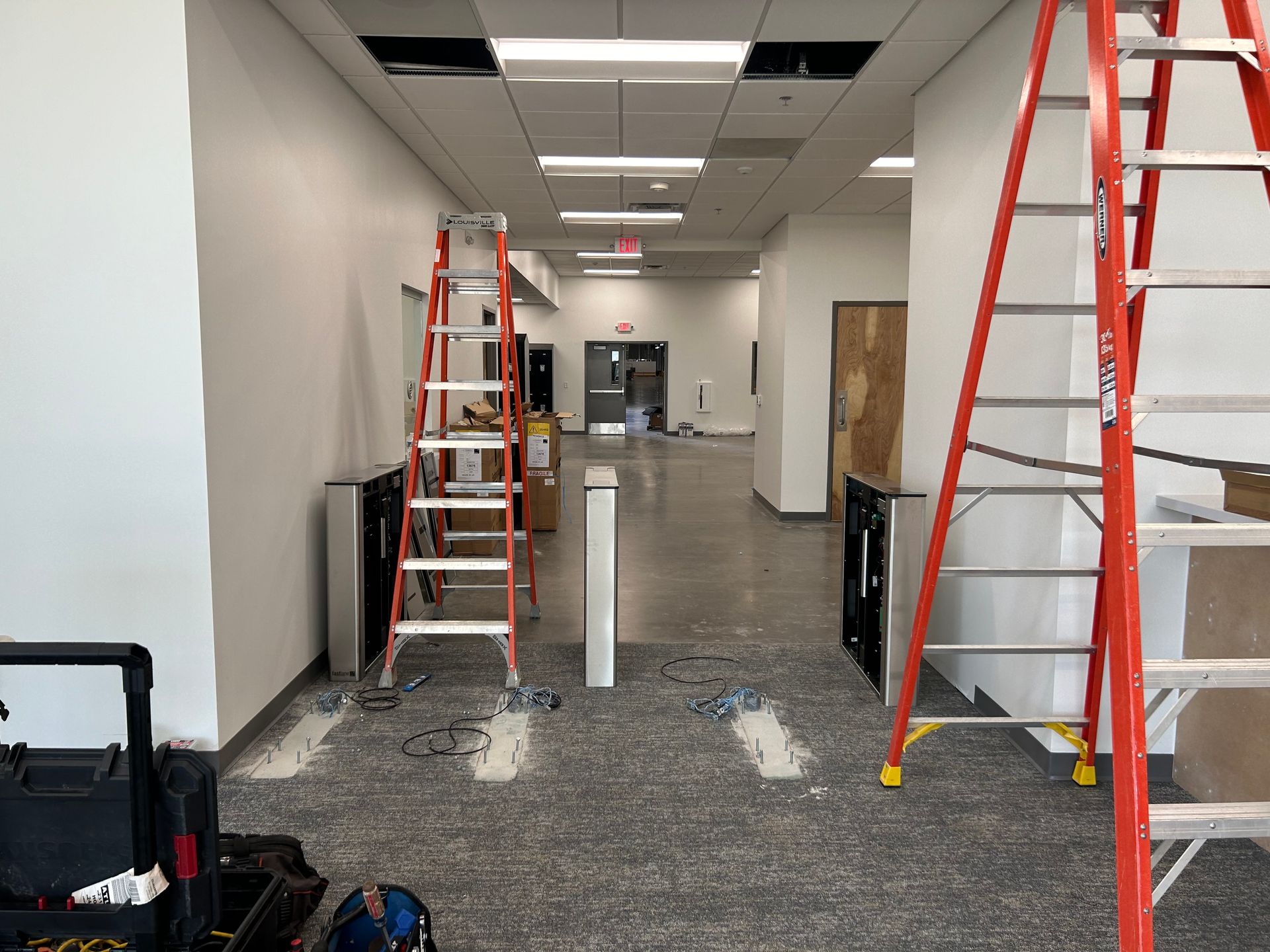 Hallway under construction with ladders, exposed floor, and equipment.