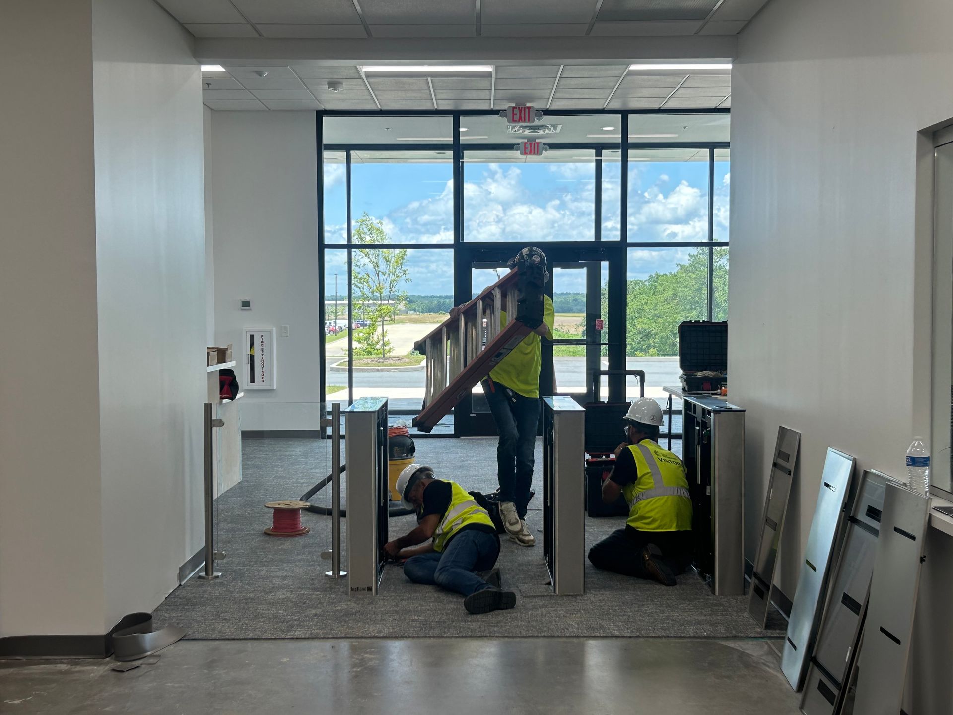 Workers installing security turnstiles in a hallway. 