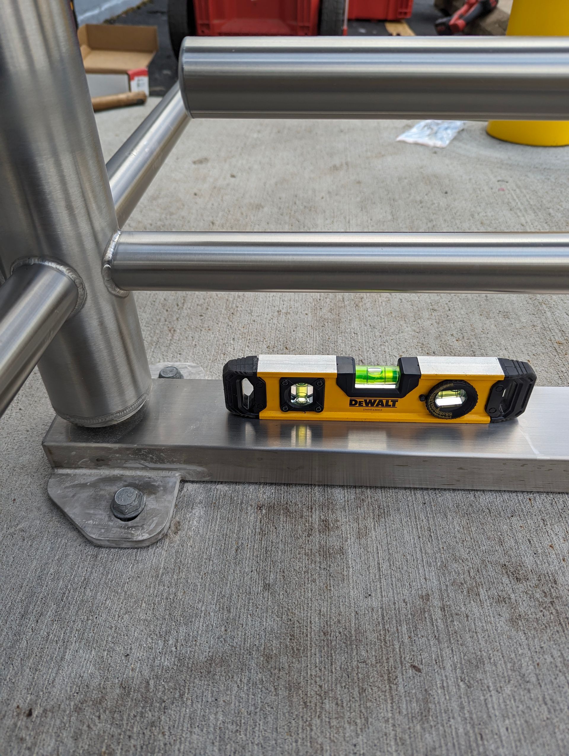 A level on a metal base of a stainless steel railing, checking for level on concrete surface.