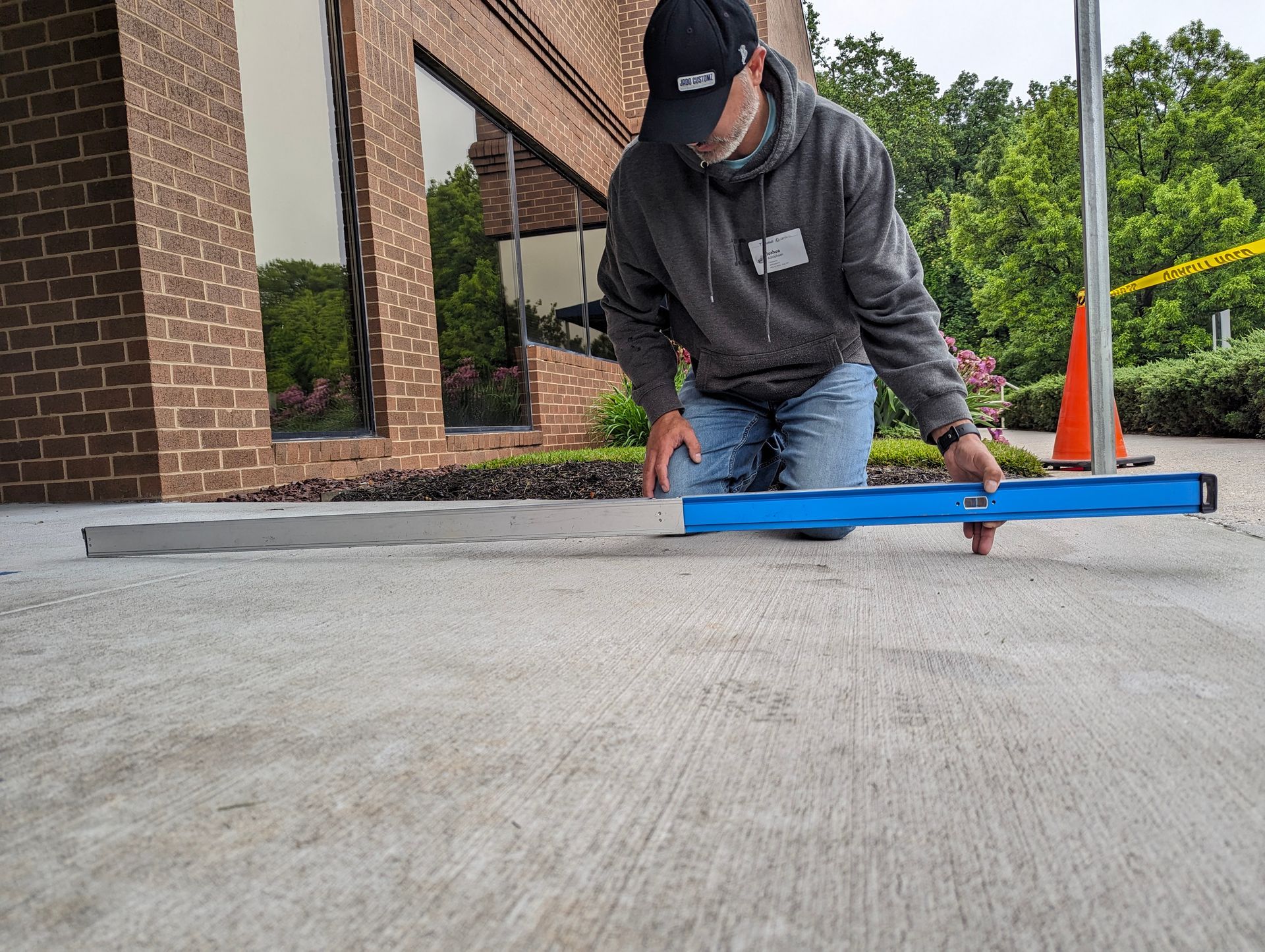 Person kneeling, using a level on concrete near a building. 