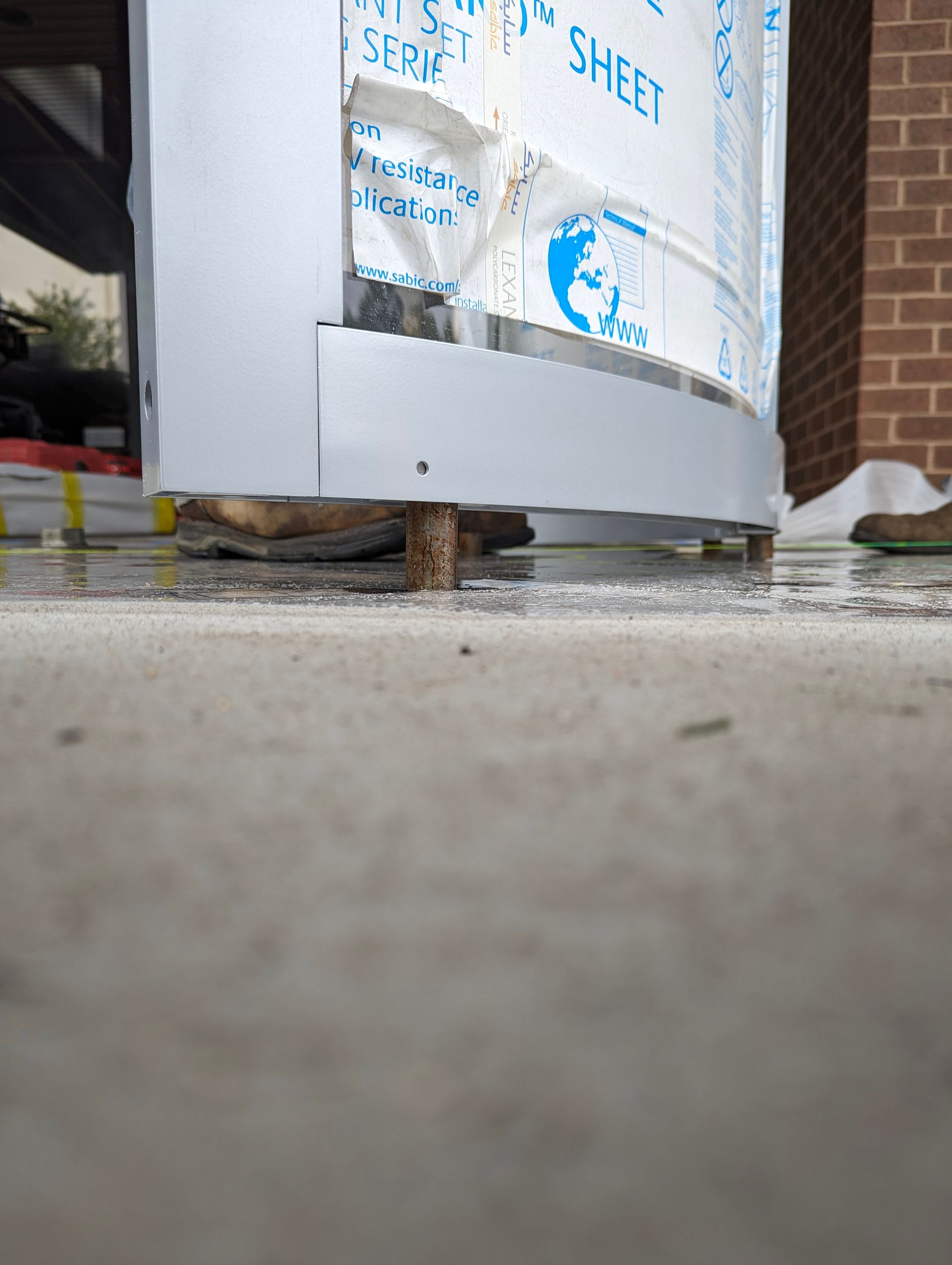 Curved metal structure on wooden blocks, resting on a concrete surface.