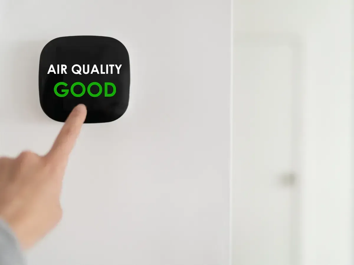 A person is pressing a button on a wall that says `` air quality good ''.