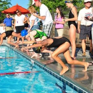 A group of people are standing around a swimming pool