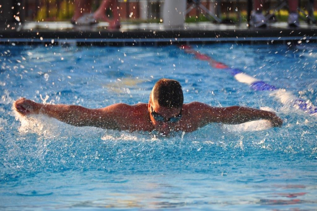 A man is swimming in a pool with his arms outstretched