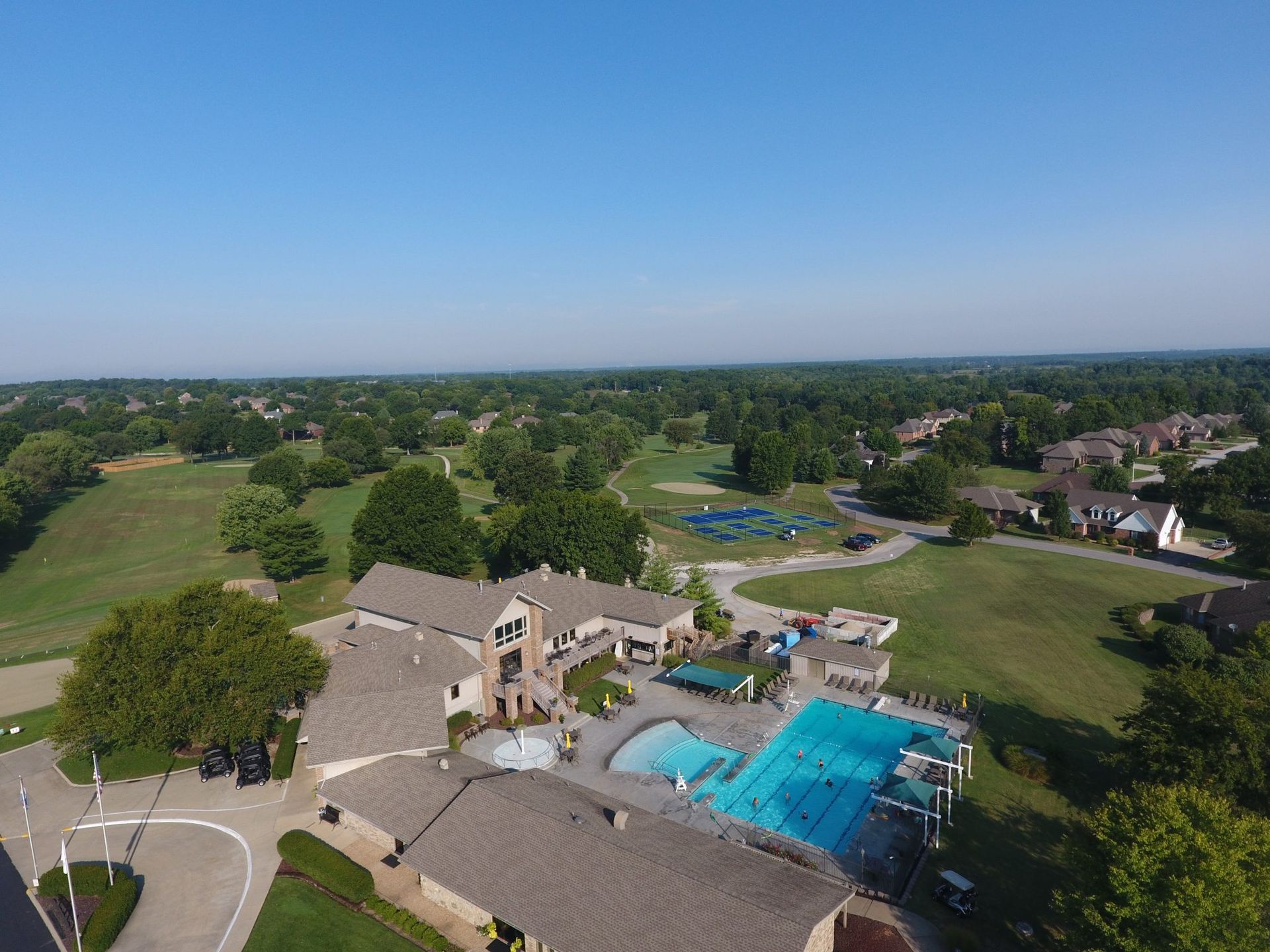 An aerial view of a golf course with a pool and a house.