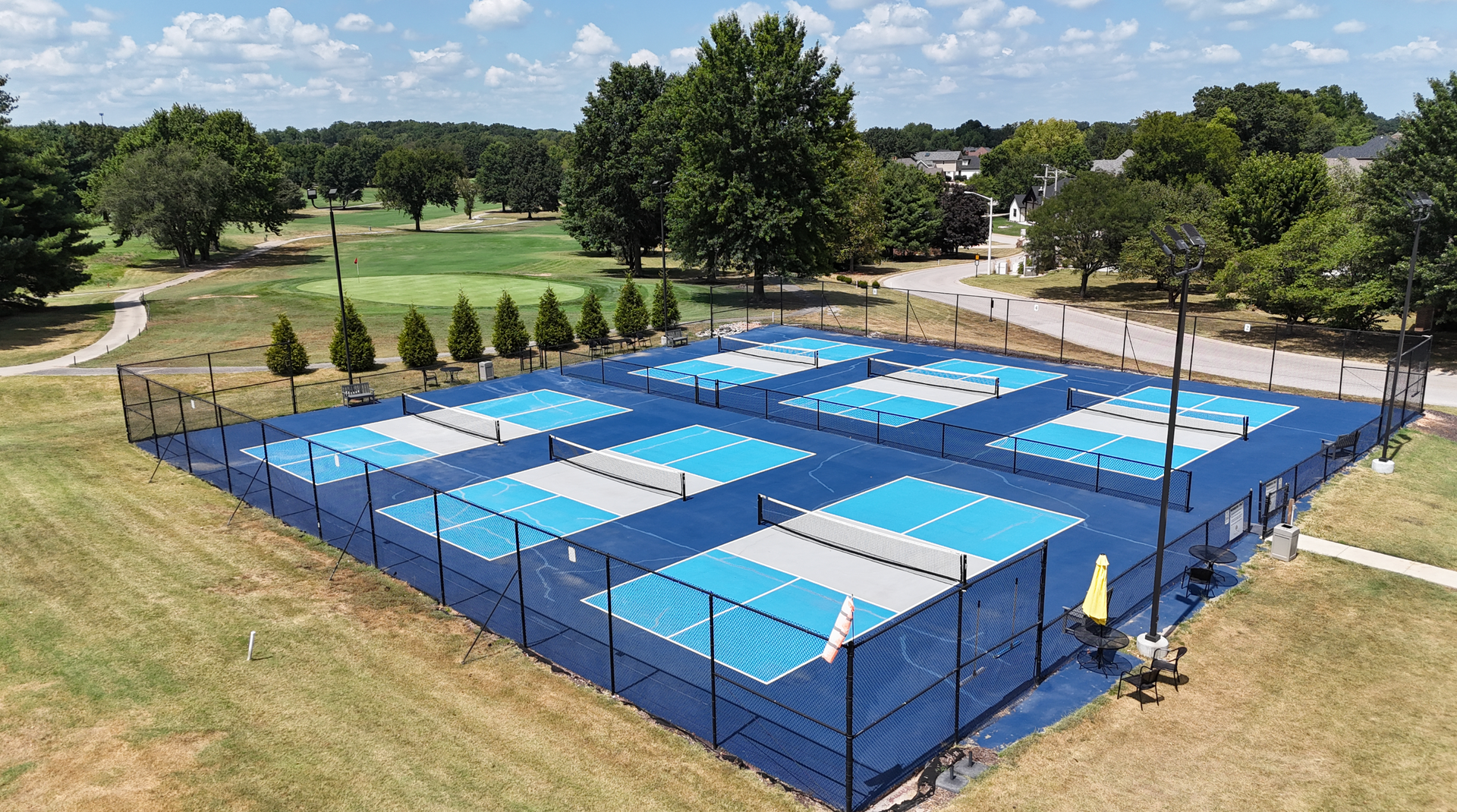 An aerial view of a tennis court with a golf course in the background