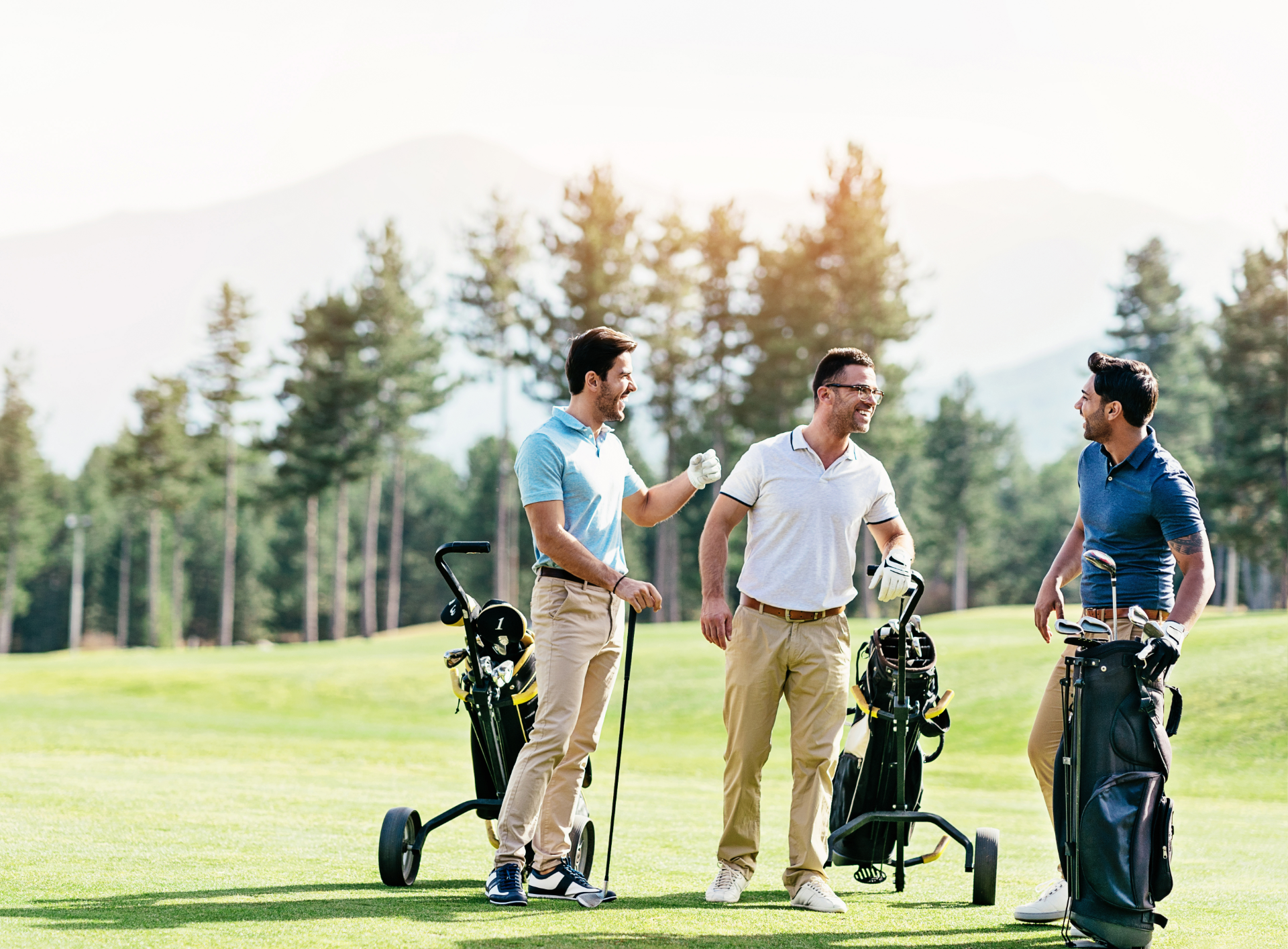 Three men are standing on a golf course talking to each other.