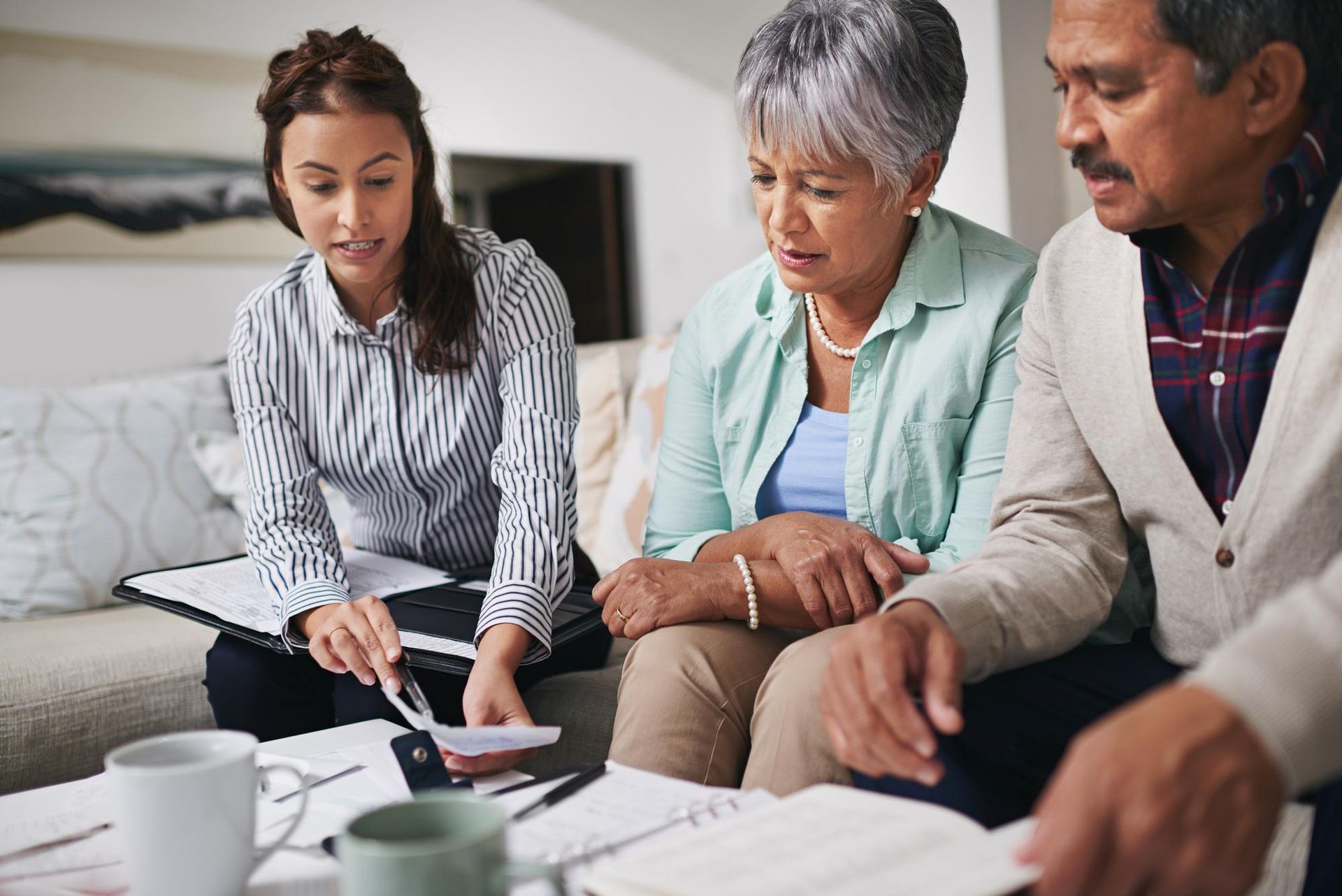 Financial advisor explaining documents to a senior couple at home.