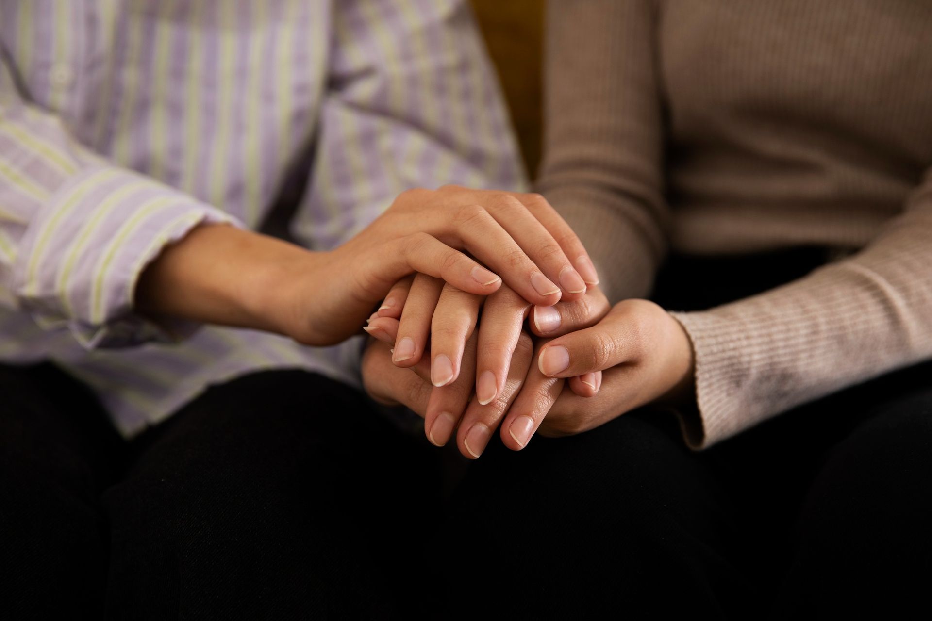 Two people hold hands, offering comfort and support.