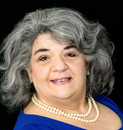 Silhouette of a person with long hair, inside a light gray circle. Dark gray top.