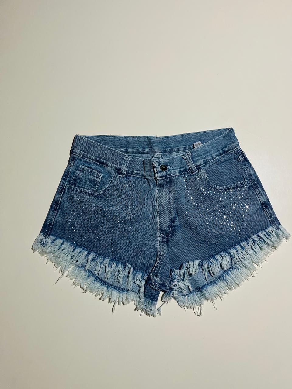 Pantalones cortos vaqueros con bajo deshilachado y detalles de salpicaduras blancas.