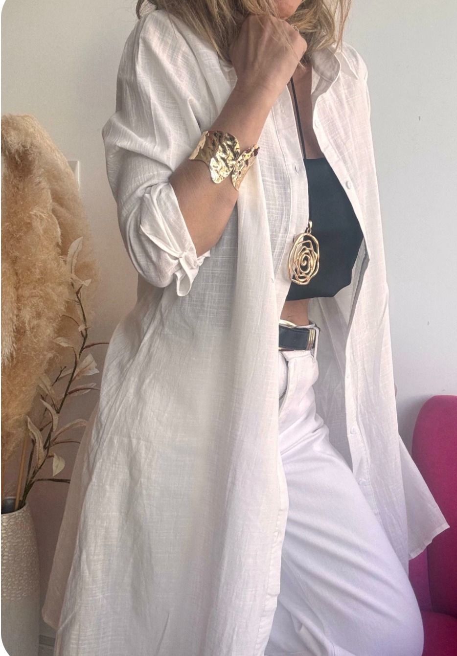 Mujer vestida de blanco con joyas de oro, posando en interiores.