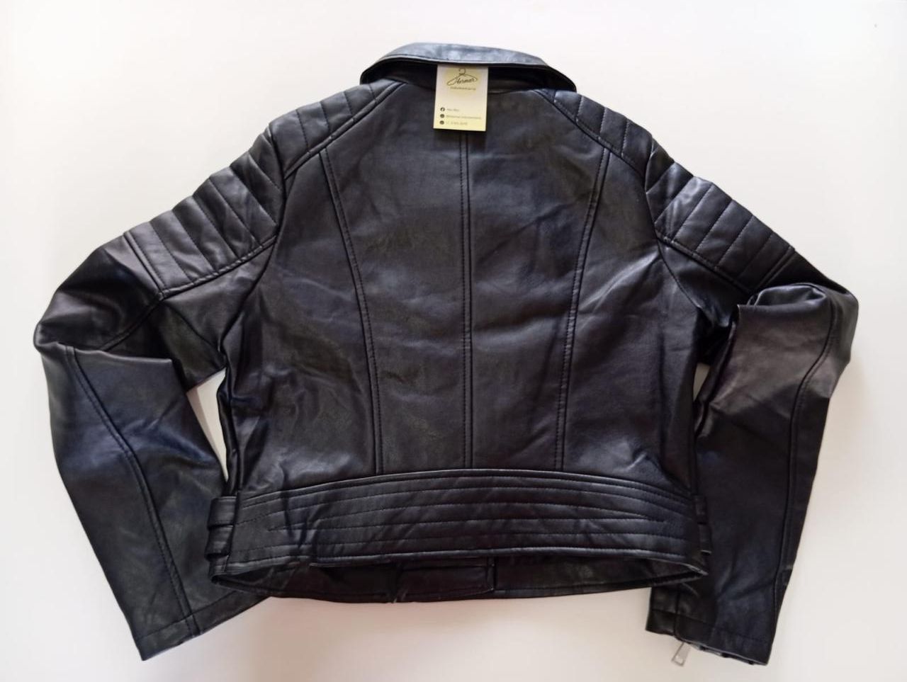 Chaqueta negra de piel sintética con cremallera asimétrica y detalles acanalados.