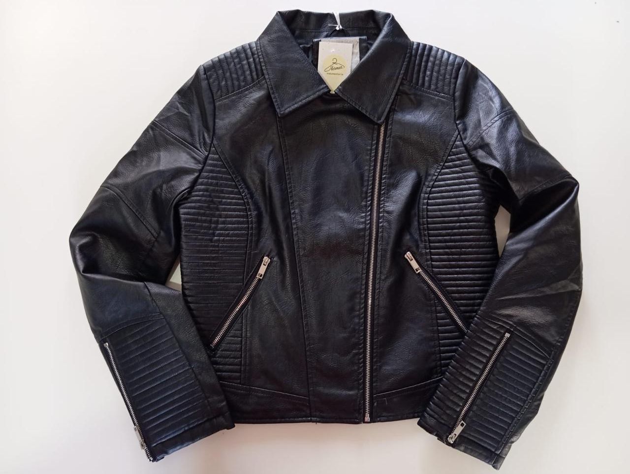 Chaqueta negra de piel sintética con cremallera asimétrica y detalles acanalados.