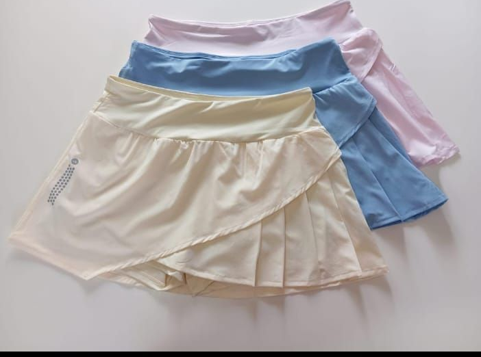 Tres faldas de tenis apiladas en color crema, azul y rosa.