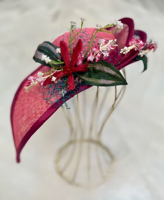 A pink hat with flowers on it is on a mannequin