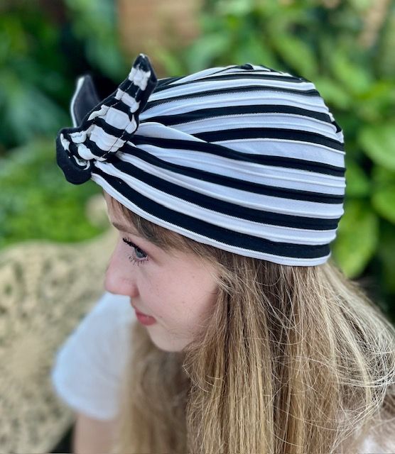 Woman wearing a black and white striped turban with a bow.