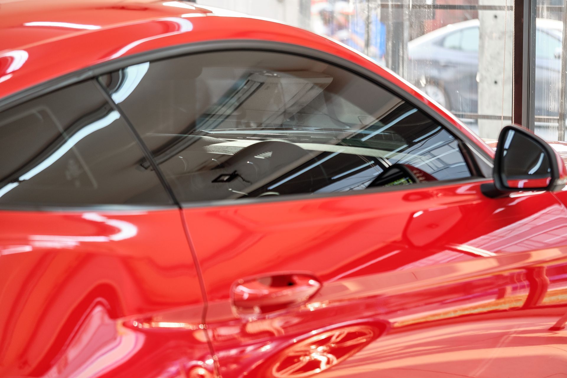Red sports car in a showroom, close-up of the side and window