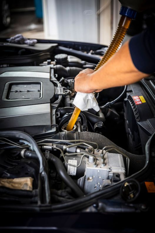 A person is pouring oil into a car engine.