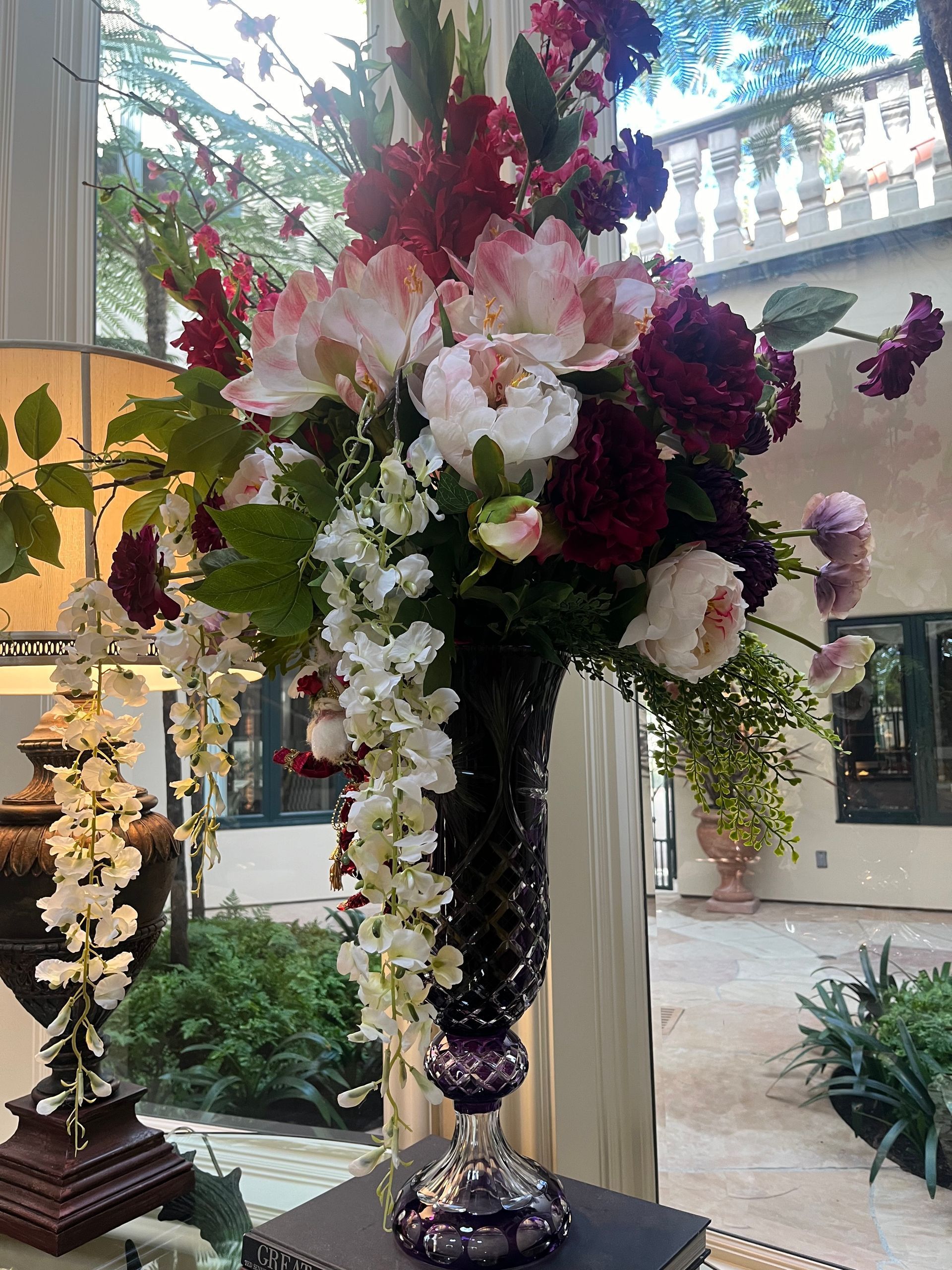 A vase filled with flowers is sitting on a table in front of a window.