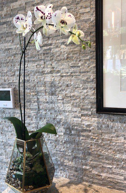 A vase filled with flowers is sitting on a table in front of a brick wall.