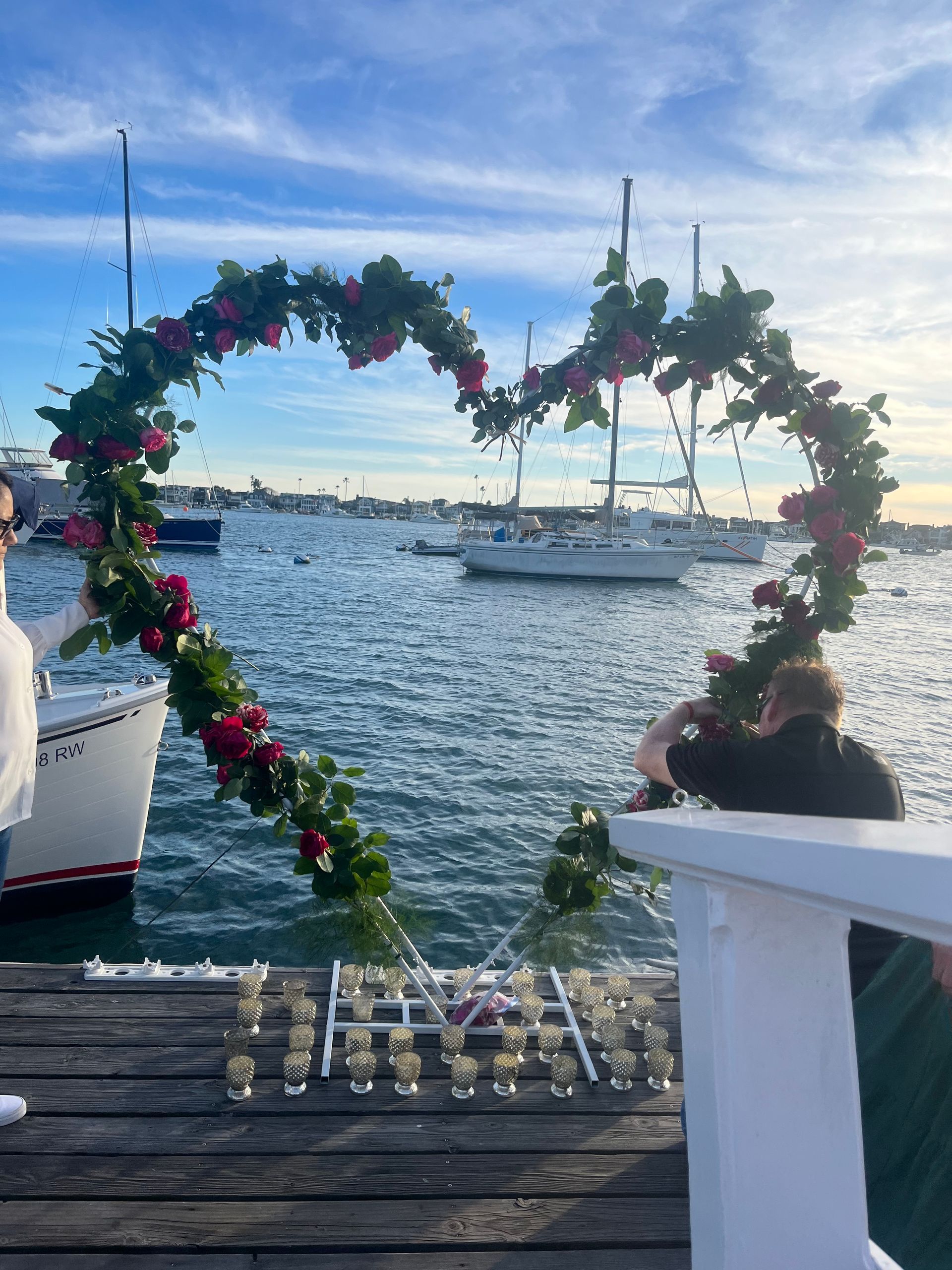 A woman is standing on a dock with a heart shaped arch in the water.