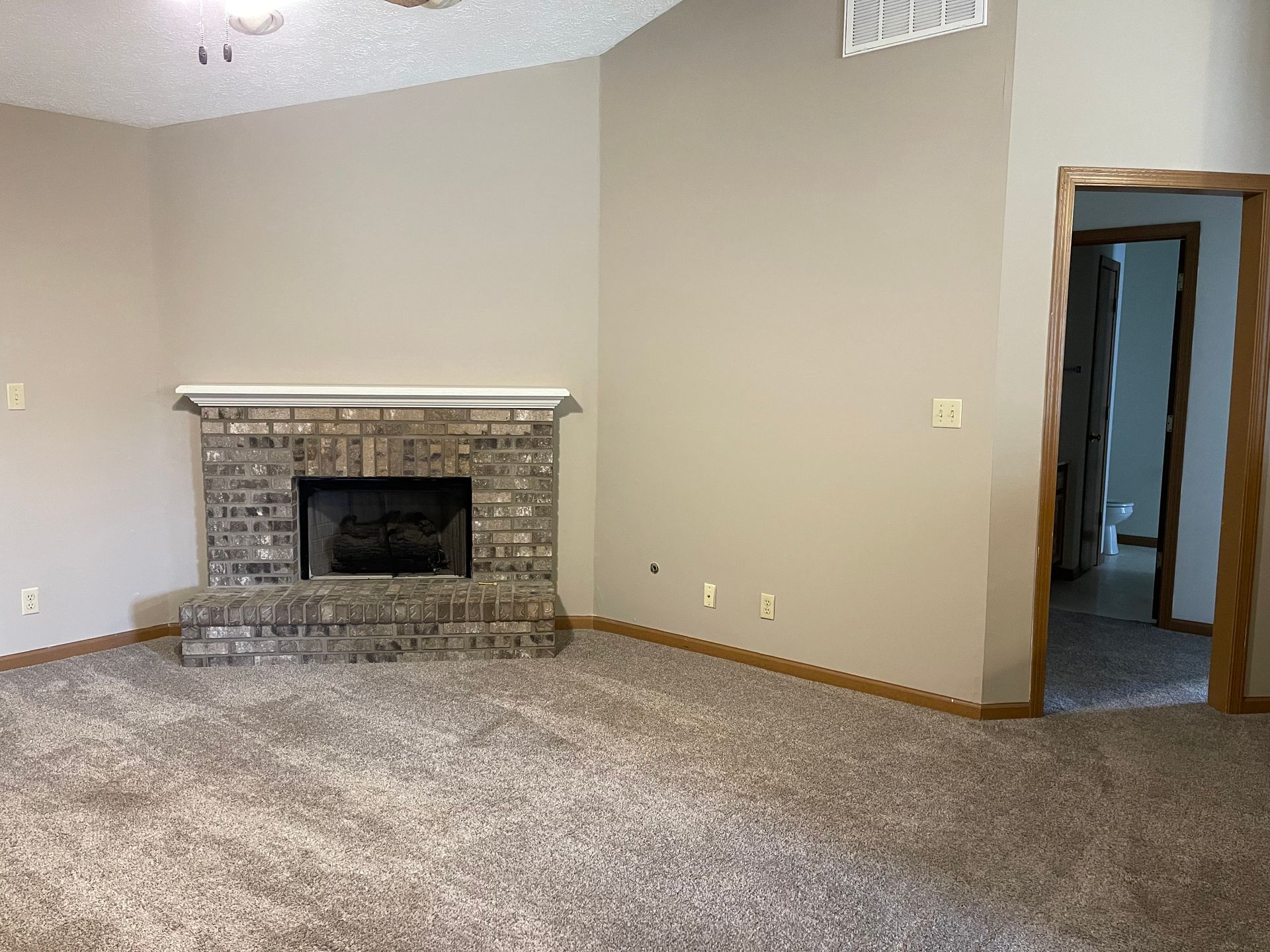an empty living room with a fireplace and carpet .
