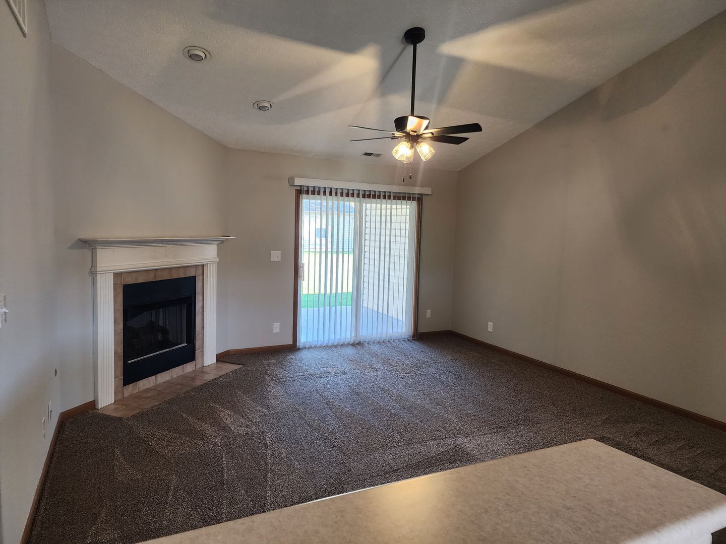 a living room with a fireplace and a ceiling fan