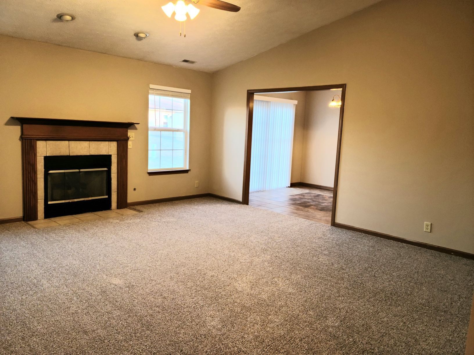 an empty living room with a fireplace and a ceiling fan