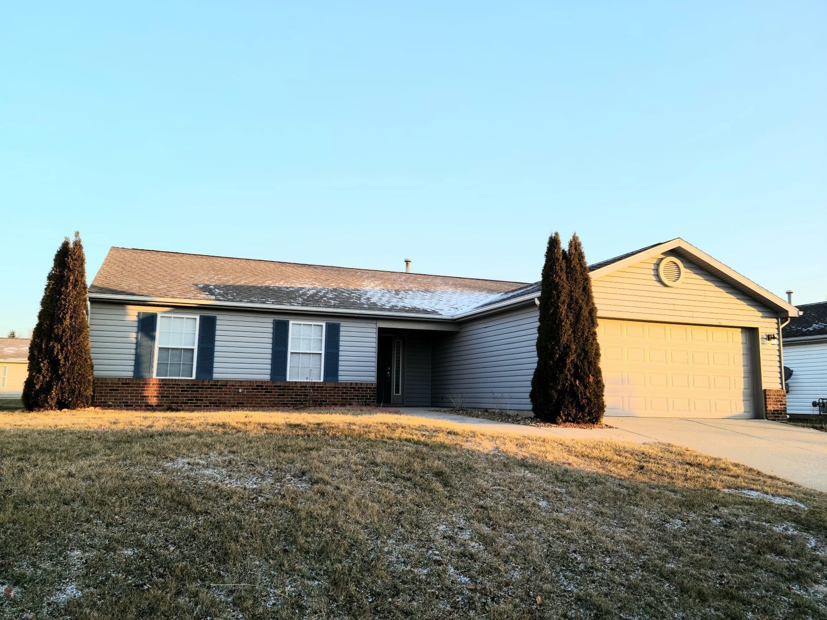 a house with a garage and two trees in front of it .