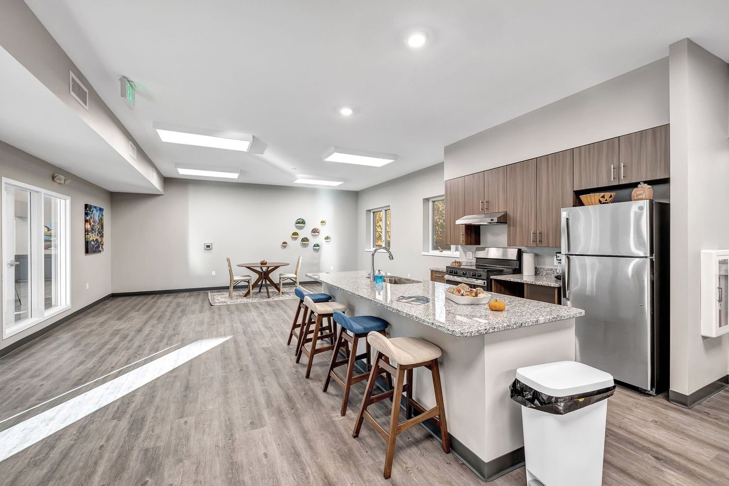 A large room with a kitchen , dining area , and trash cans.