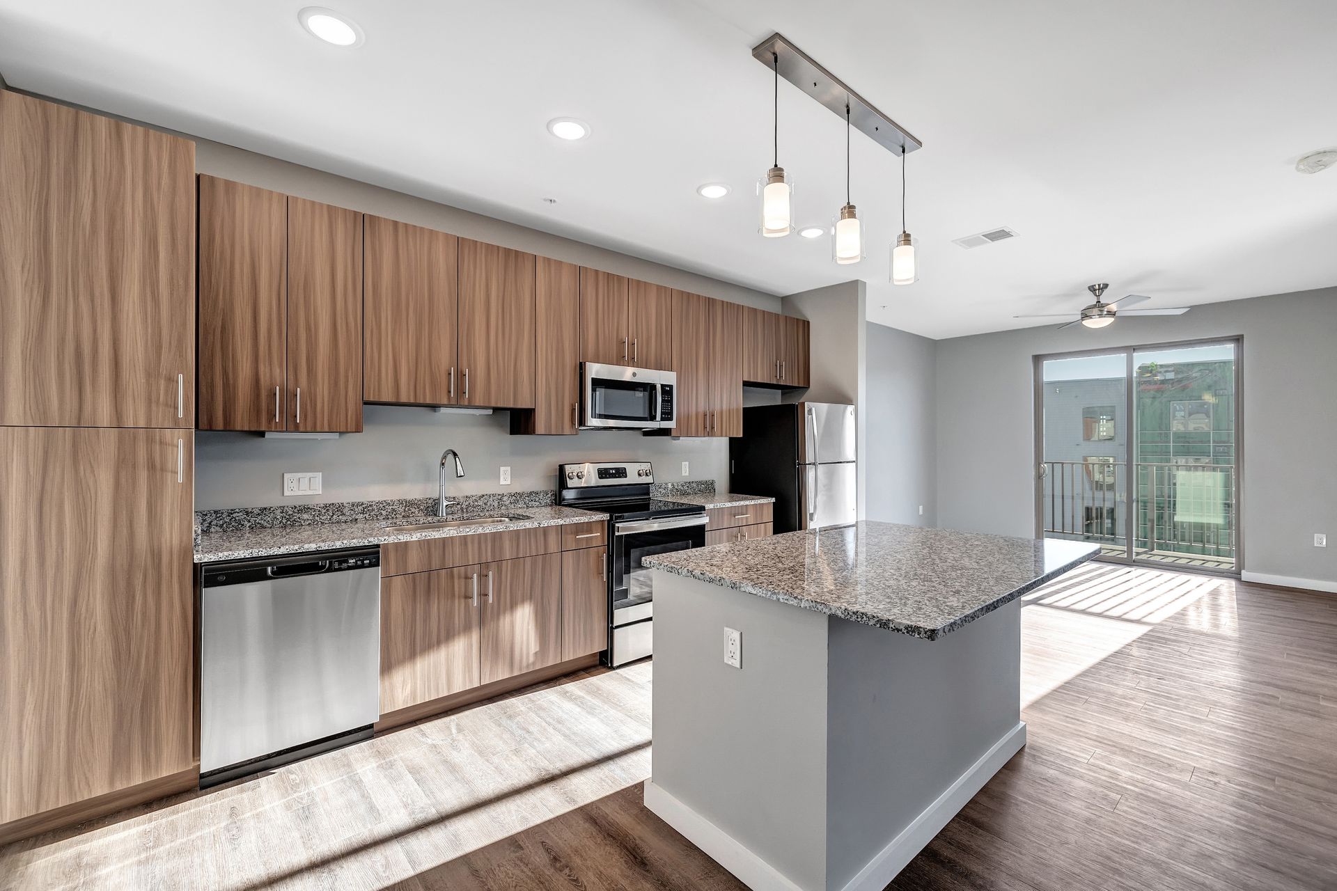 A kitchen with stainless steel appliances , wooden cabinets , granite counter tops and a large island.