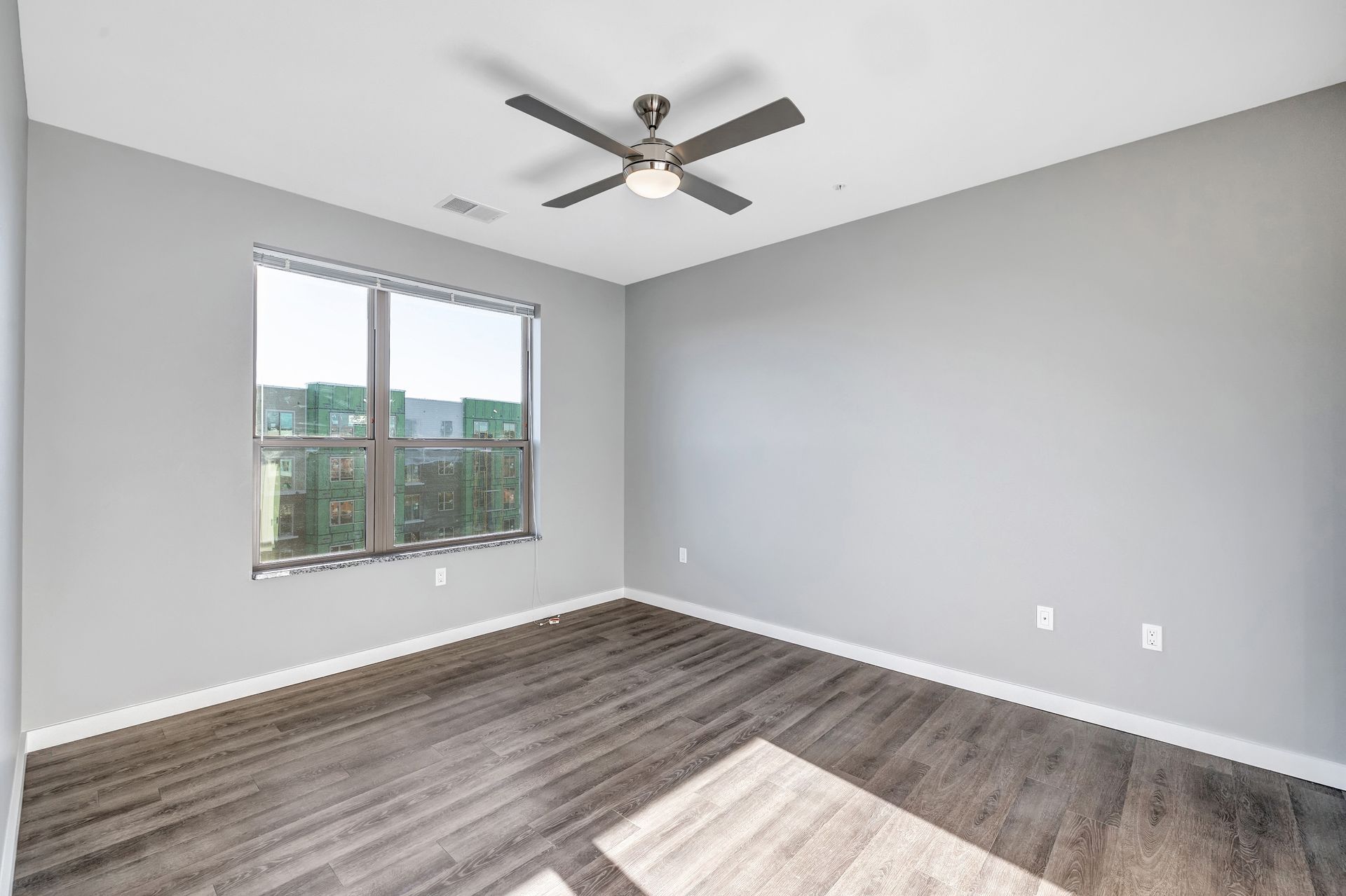 An empty room with a ceiling fan and a window.
