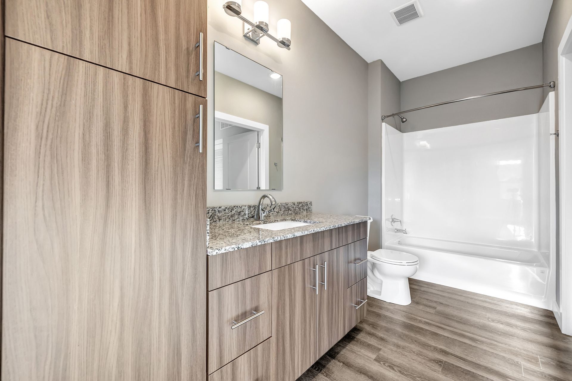 A bathroom with a sink , toilet , tub and mirror.