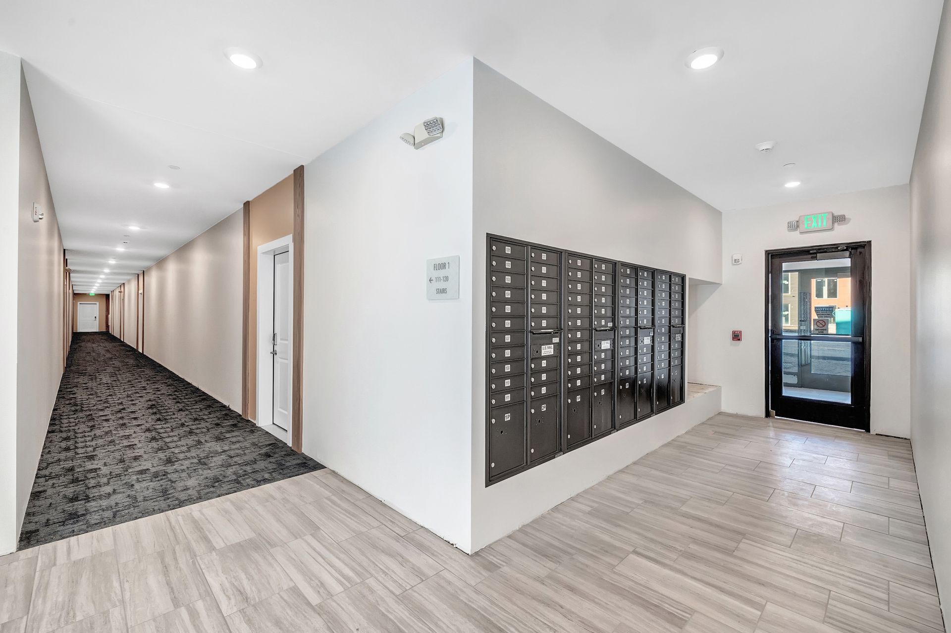 A long hallway with a lot of mailboxes on the wall.