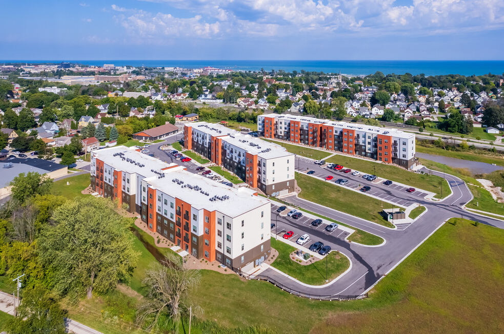 An aerial view of a large apartment complex with a lot of cars parked in front of it.