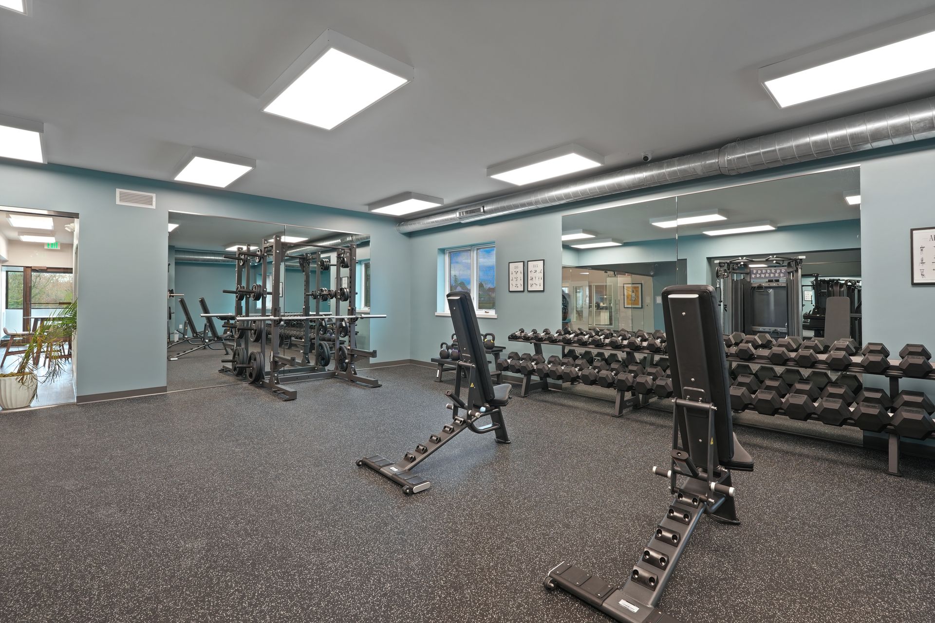A large gym with a lot of dumbbells and benches