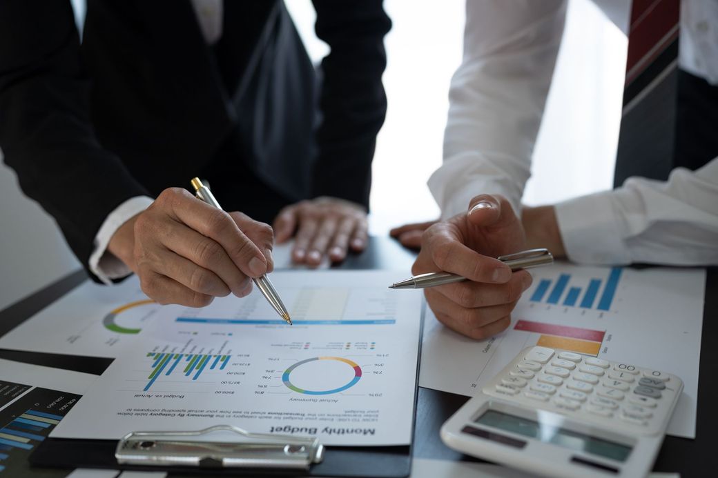 A group of business people are sitting at a table looking at a graph.